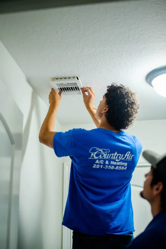 A Country Air technician refitting a ceiling register inside a Magnolia home